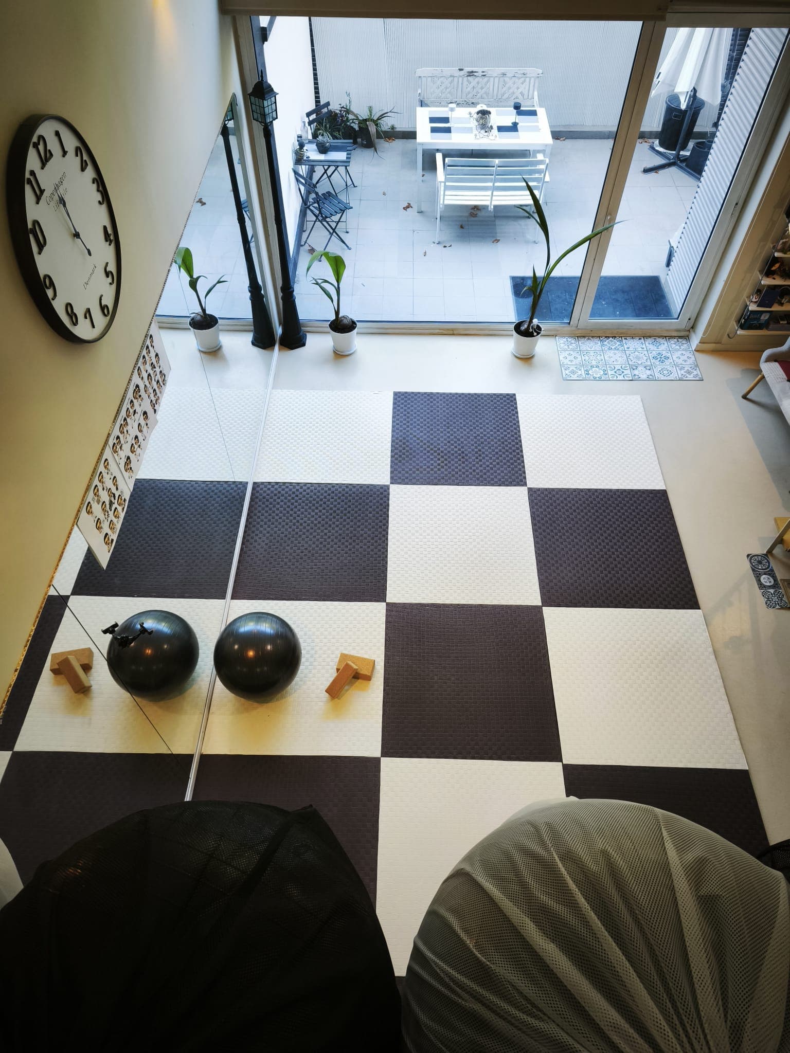 La sala vista desde el altillo: el suelo ajedrezado, dos pelotas, dos bloques y la terraza al fondo tras la cristalera.